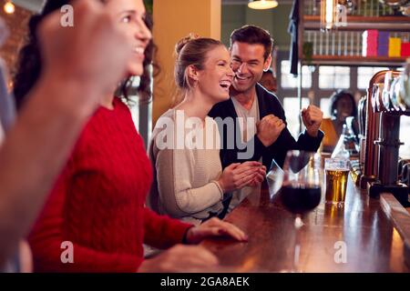 Gruppo di clienti entusiasti in Sports Bar Watching Sporting Event on Television Foto Stock