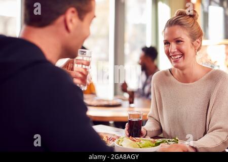 Una coppia sorridente in data gustando la pizza al ristorante insieme Foto Stock