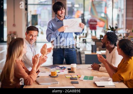 Colleghi Applaauding come uomo d'affari dà la presentazione nel moderno ufficio di piano aperto Foto Stock