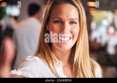 Ritratto di giovane Businesswoman che prende Selfie sul telefono cellulare in un moderno ufficio Open Plan Foto Stock