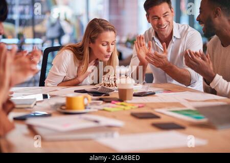 I colleghi celebrano il compleanno di Businesswoman al Meeting Around Table nel moderno ufficio Open Plan Foto Stock