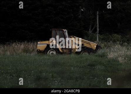 Il trattore abbandonato è stato lasciato arrugginire in un campo in cui è stato abbandonato Foto Stock