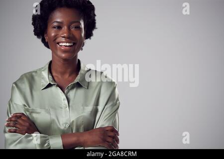 Primo piano Studio Portrait of Smiling Young Businesswoman with Folded Arms Against Plain background Foto Stock