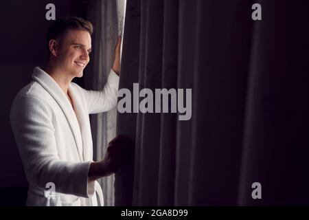 Uomo che indossa accappatoio sull'hotel o sulle tende di apertura del Spa Break Foto Stock