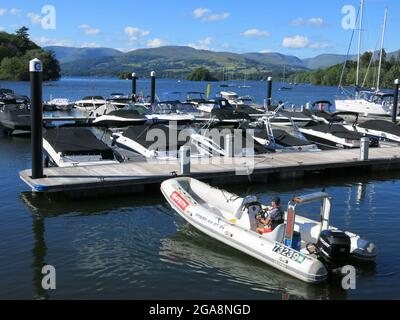 Una bella giornata estiva sul lago Windermere e la dinghia di sicurezza lasciano il molo di Bowness per dirigersi verso il lago. Foto Stock