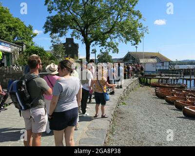I passeggeri si accodano per il traghetto sul lago Windermere che naviga tra Ambleside e Bowness; una giornata estiva soleggiata in una staycation Lake District. Foto Stock