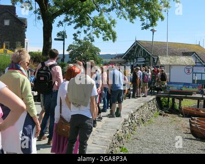 I passeggeri si accodano per il traghetto sul lago Windermere che naviga tra Ambleside e Bowness; una giornata estiva soleggiata in una staycation Lake District. Foto Stock