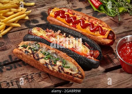 Tre hot dog con vari ripieni di patatine fritte, salsa Foto Stock