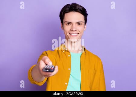 Foto di brunetto impresso giovane ragazzo orologio tv indossare camicia marrone isolato su sfondo di colore viola Foto Stock