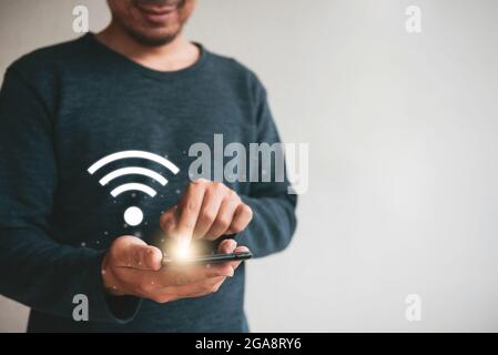 Primo piano mani che tengono smartphone. Uomo che usa il cellulare connessione wi-fi per il marketing e la ricerca di dati e social media su internet.Technology busine Foto Stock