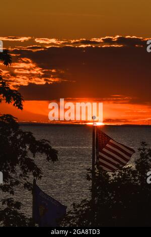 Bandiera americana che balzava nel vento con il magnifico tramonto su Green Bay (lago Michigan) visto dal parco di Egg Harbor, Door County, Wisconsin, USA Foto Stock