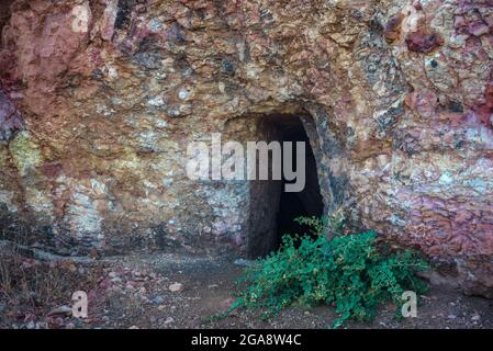 Abbandonato miniera d'oro adit in Troodos montagne vicino Analiontas, Cipro. Le rocce colorate sono usuali per questa zona ricca di minerali di rame e solfuri Foto Stock