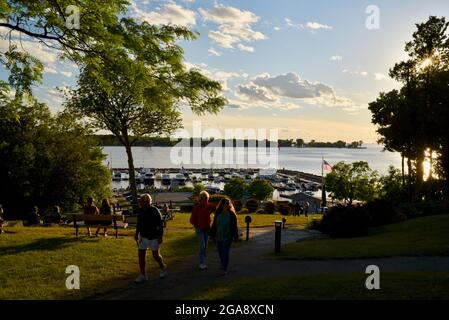 Le persone si rilassano sulle panchine nel parco, guardando il magnifico tramonto, affacciato sul porto con le barche, a Egg Harbor, Door County, Wisconsin, USA Foto Stock