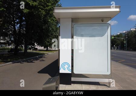 Fermata dell'autobus cittadino sulla strada. Alla fermata dell'autobus bianco poster bianco per la pubblicità. Estate giorno di sole. Foto Stock