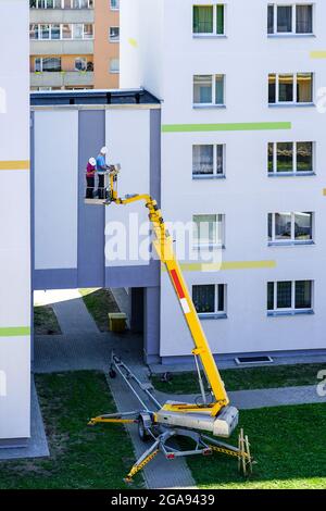 lo specialista ispeziona la facciata della casa con l'aiuto di una moderna piattaforma di sollevamento idraulico semovente mobile Foto Stock