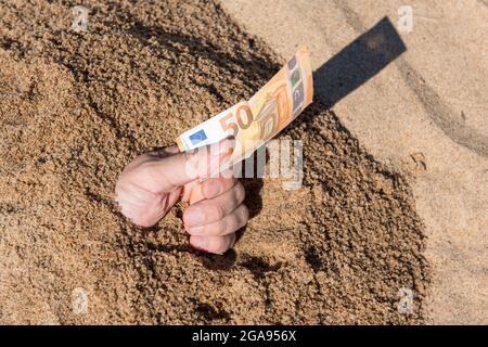 Cinquanta euro in mano di un uomo che si stacca dalla sabbia Foto Stock