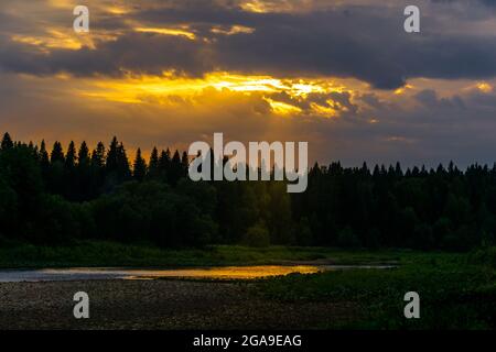 tramonto estivo sul fiume settentrionale con rive boscose selvagge Foto Stock
