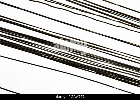 Disordine silhouette linea disordinata di fili elettrici neri isolati su fondo bianco chiaro. Numerosi cavi telefonici elettrici caotici con cielo Foto Stock