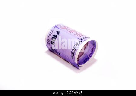 Indiano cento rupie arrotolato banconota isolato su sfondo bianco. Foto Stock