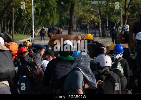 Medellin, Colombia. 28 luglio 2021. I manifestanti in prima linea utilizzano cartelli stradali e scudi artigianali per coprire i barattoli di gas lacrimogeni, mentre le manifestazioni si sono concluse in scontri notturni tra la polizia in rivolta della Colombia (ESMAD) e i dimostranti, mentre la Colombia segna 3 mesi di proteste anti-governative contro il governo colombiano Ivan Duque, e una nuova riforma fiscale tra disordini e violenza che ha lasciato almeno 83 morti dall’inizio delle proteste. Il 28 luglio 2021 a Medellin - Antioquia, Colombia. Credit: Long Visual Press/Alamy Live News Foto Stock