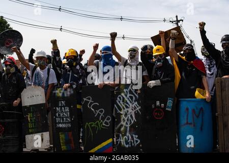 Medellin, Colombia. 28 luglio 2021. I dimostranti della prima linea che usano caschi da costruzione e scudi artigianali sollevano i pugni mentre le manifestazioni si sono concluse in scontri notturni tra la polizia in rivolta della Colombia (ESMAD) e i dimostranti, mentre la Colombia segna 3 mesi di proteste anti-governative contro il governo colombiano Ivan Duque, e una nuova riforma fiscale tra disordini e violenza che ha lasciato almeno 83 morti dall’inizio delle proteste. Il 28 luglio 2021 a Medellin - Antioquia, Colombia. Credit: Long Visual Press/Alamy Live News Foto Stock