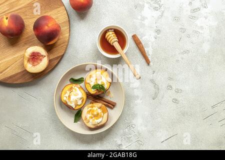 Pesche cotte su un piatto con foglie di menta, cannella, formaggio cremoso non caseario, miele e fiocchi di mandorle. Foto Stock