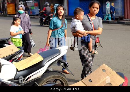 Una passeggiata per la famiglia sulla strada. Solo uno di loro indossa il facemask. Foto Stock