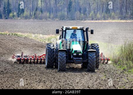 Campo coltivatore con trattore verde Deutz-Fahr Agrotron 135 e erstad NZ con erpice a denti aggressivo in primavera. Salo, Finlandia. 13 maggio 2021 Foto Stock