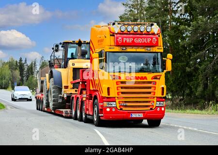 Il dumper personalizzato Scania G580 del gruppo PHP davanti al rimorchio a collo d'oca trasporta la pala gommata Cat sull'autostrada 2. Jokioinen, Finlandia. 14 maggio 2021. Foto Stock
