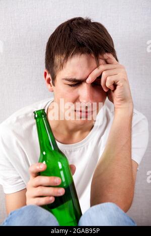 Triste giovane uomo con una birra al muro Foto Stock