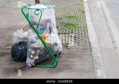 Sacchi per rifiuti sullo sfondo sporco del marciapiede Foto Stock