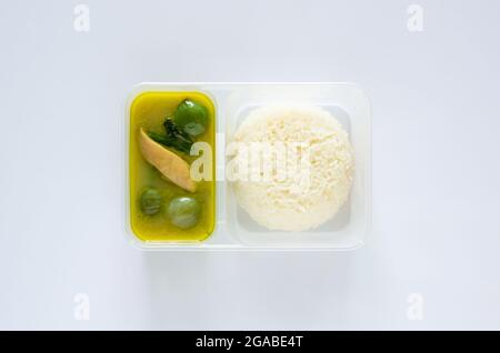 Vista dall'alto del curry thai verde con riso gelsomino in scatola di plastica su sfondo bianco. Foto Stock