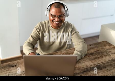 Felice uomo anziano che lavora in modo intelligente utilizzando il laptop a casa - concetto di tecnologia Foto Stock