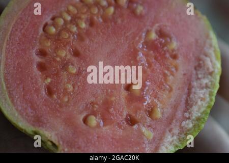 Molto closeup vista di taglio gustoso frutto guava con semi, miele molto gustoso frutta di guava maturata sulla mano Foto Stock