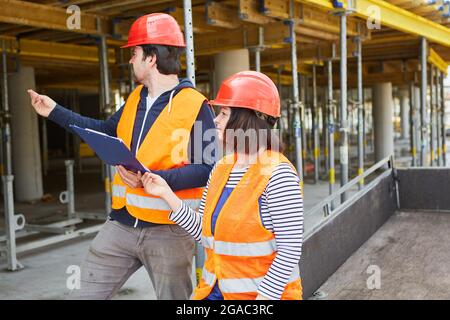 Un esperto di costruzioni e un architetto effettuano un'ispezione insieme in un cantiere di costruzione di fronte al nuovo edificio Foto Stock