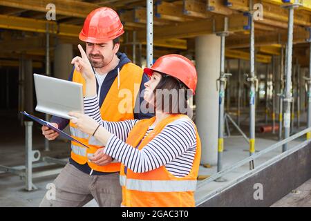 Architect with Tablet computer parla di progetto di costruzione con il caposquadra nel cantiere della shell Foto Stock