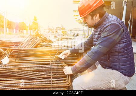 Il lavoratore controlla la consegna di acciaio di rinforzo sul cantiere per una costruzione di casa Foto Stock