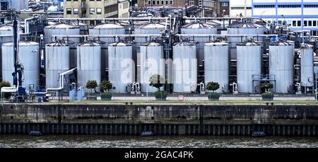 Serbatoi di stoccaggio per petrolio e benzina al bordo di un bacino portuale su un fiume Foto Stock