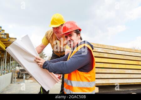 Architetto e lavoratore di costruzione insieme su un cantiere con pianta del pavimento durante la pianificazione della costruzione Foto Stock