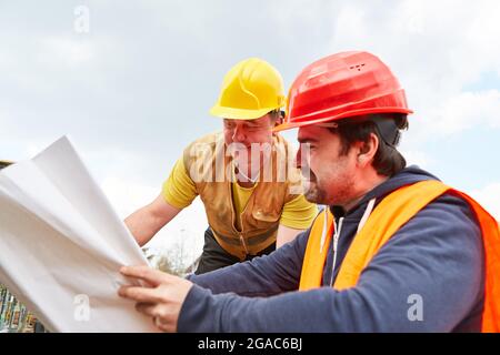 Architetto e artigiano del cantiere guardano il disegno della costruzione per la progettazione della costruzione Foto Stock