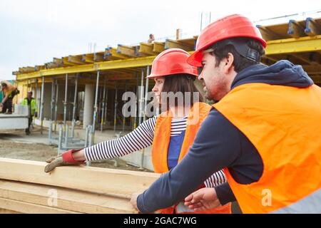 Carpentieri artigiani squadra di scaricare una consegna di legname sul cantiere da casa costruzione Foto Stock