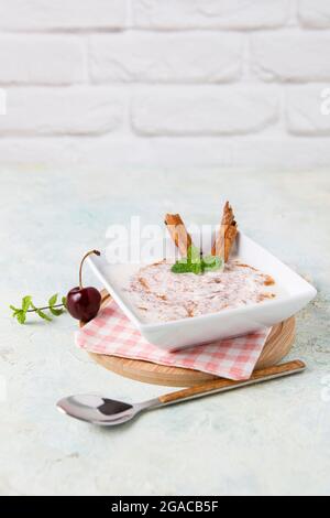 Budino di riso fatto in casa con cannella e ciliegie in una ciotola bianca su legno Foto Stock