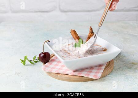 Budino di riso fatto in casa con cannella e ciliegie in una ciotola bianca su legno Foto Stock