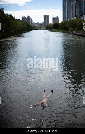 Pechino, Cina. 30 luglio 2021. L'uomo nuota nel fiume Liangma passando per il centro di Pechino, Cina il 30/07/2021 da Wiktor Dabkowski Credit: dpa/Alamy Live News Foto Stock