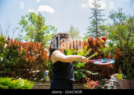 Bambina che gioca a tennis nel suo giardino in una giornata estiva. Focus Girl selettivo Foto Stock