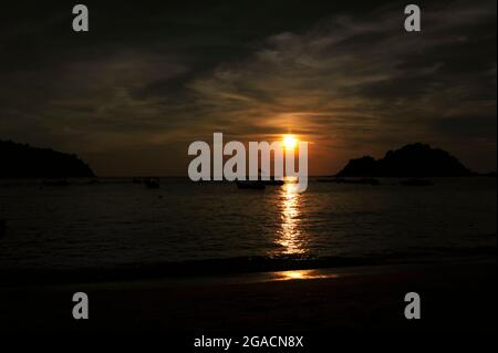 Vista del tramonto su una spiaggia con barche nel mare a Pangkor Island, Malesia Foto Stock