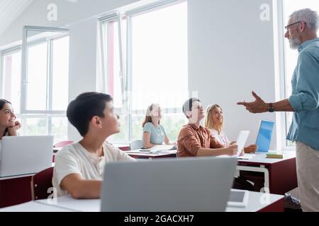 studenti adolescenti multiculturali che ascoltano insegnanti di mezza età che parlano durante la lezione Foto Stock