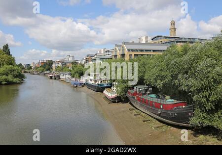 Casa barche ormeggiate sulla riva nord del Tamigi a ovest di Kew Bridge, Londra, Regno Unito. Gli scafi riposano sui fasci di timver per mantenerli a livello alla bassa marea. Foto Stock