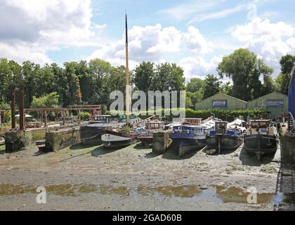 Le case galleggianti si siedono sul fango fluviale a bassa marea a Johns Boatworks on Lots Ait - un'isola nel Tamigi a Brentford, Londra ovest, Regno Unito Foto Stock