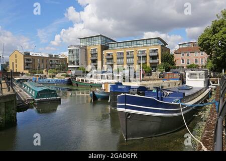 Le case galleggianti e le chiatte ormeggiate presso un molo riprogettato sul Tamigi a Brentford, Londra ovest, Regno Unito. Nuovi caffè e appartamenti in background. Foto Stock